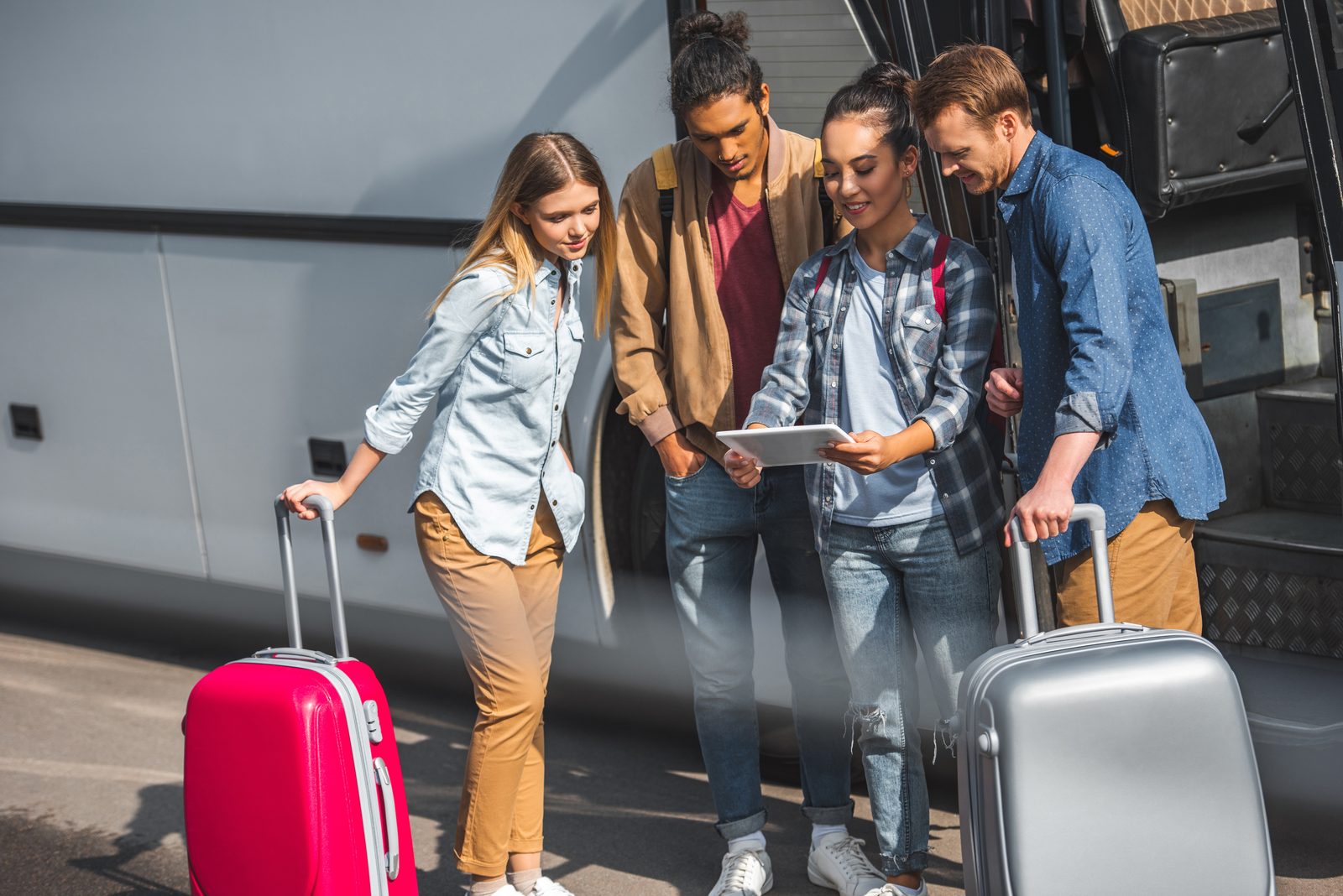 Travelers checking a booking on a tablet beside a coach