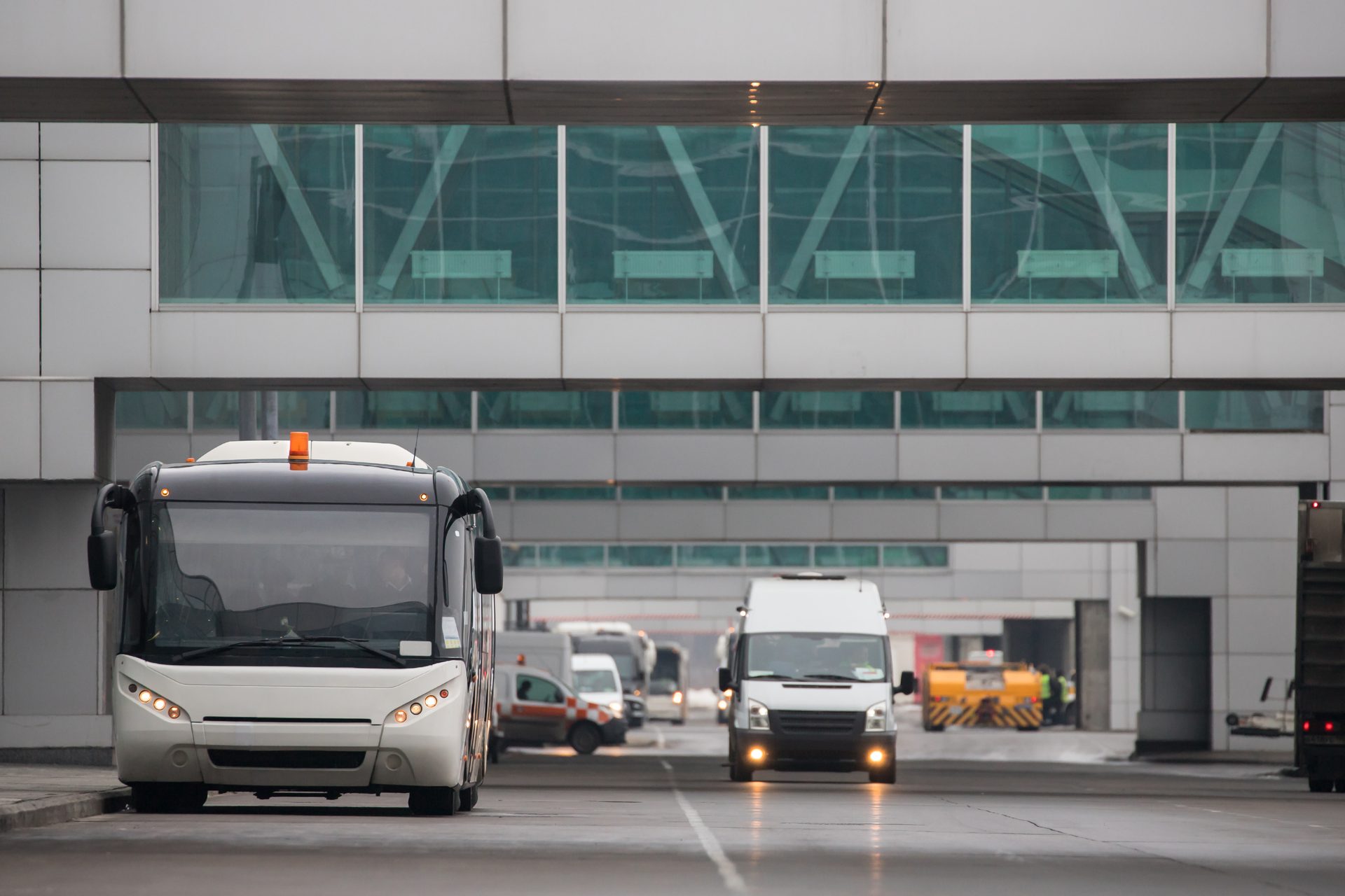 Sample airport shuttle website: a white passenger van and an apron bus beneath a glass airport terminal bridge