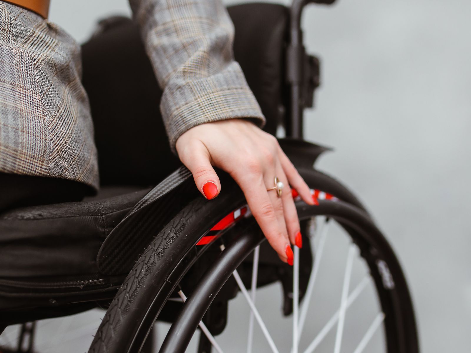 A rider's hand resting on the wheel of a wheelchair